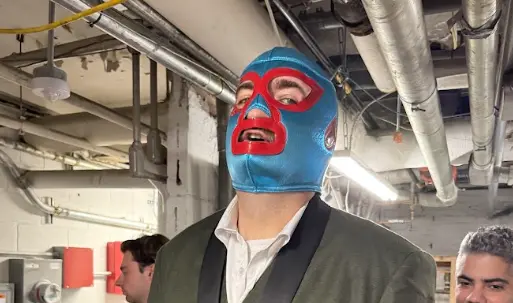 A masked performer prepares backstage