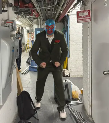 A masked performer in the backstage corridor